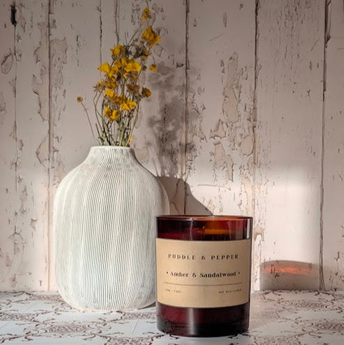 Candle and vase on a textured surface with wooden wall background